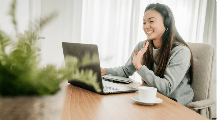 Happy woman working from home with headphones and laptop in a bright, comfortable space